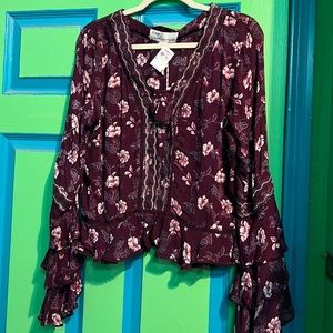 Medium long sleeve maroon blouse with flowers. Has a bow that ties in the front